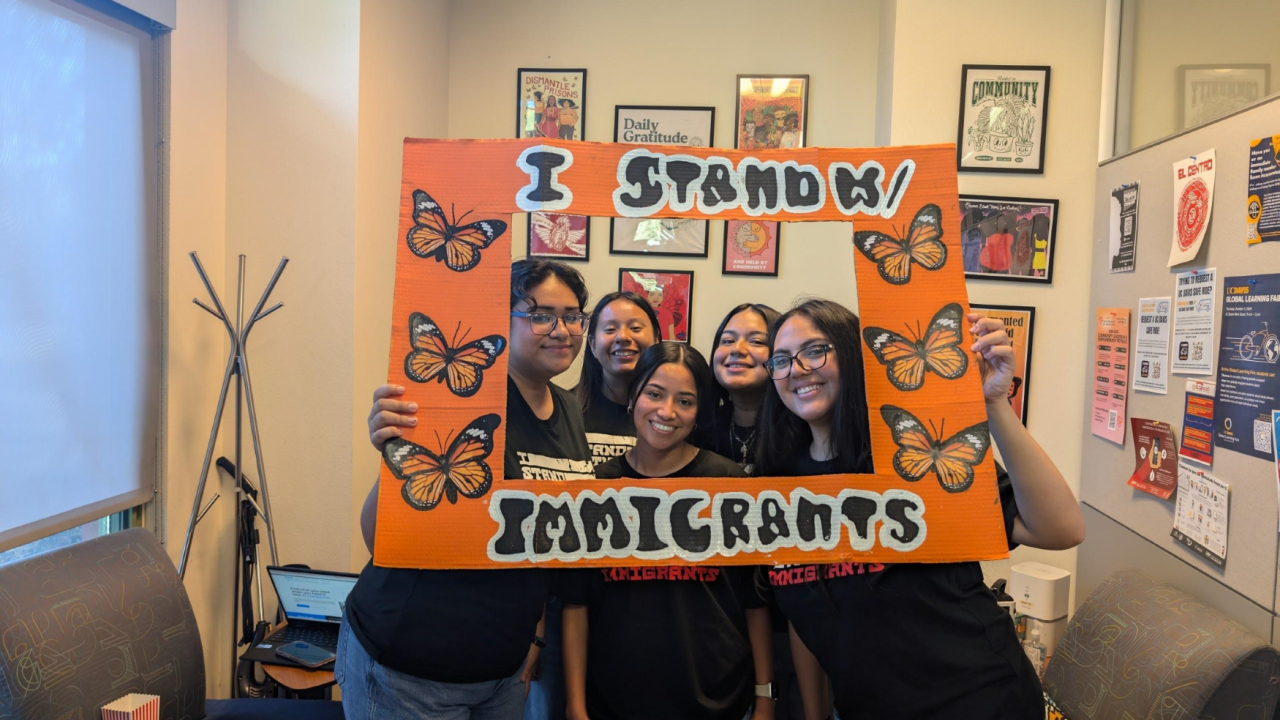SPEAK student members posing in front of a frame that read "I Stand With Immigrants" from UndocuWelcome 2024