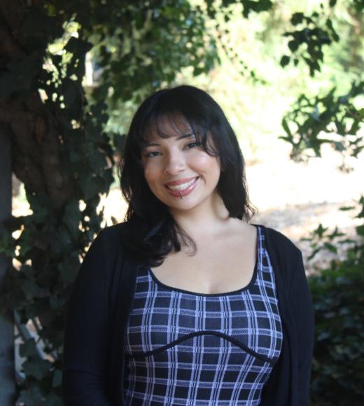 Sarai smiling warmly in front of greenery background