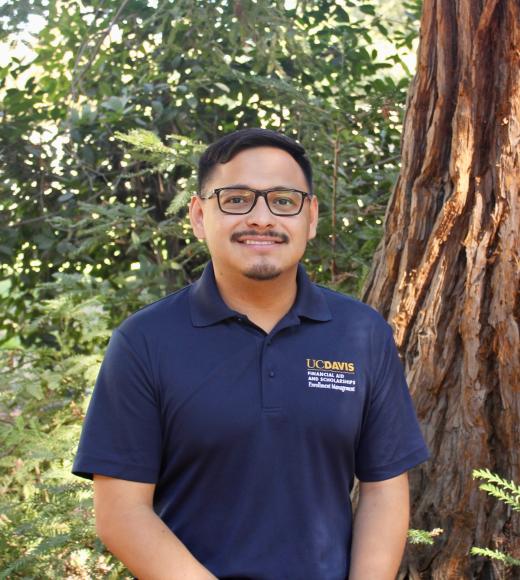 Leo Flores smiling warmly at camera in front of greenery backgroung.