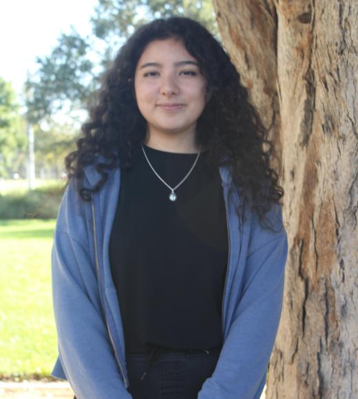 Danna standing in front of a tree. Greenery background.