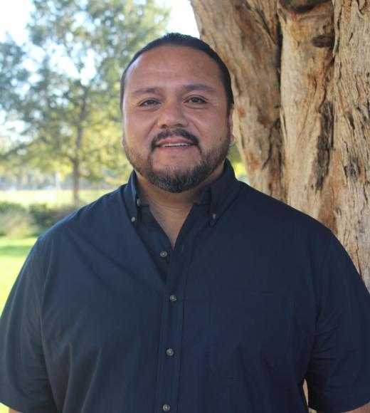 Edgar standing in front of a tree. Greenery background.