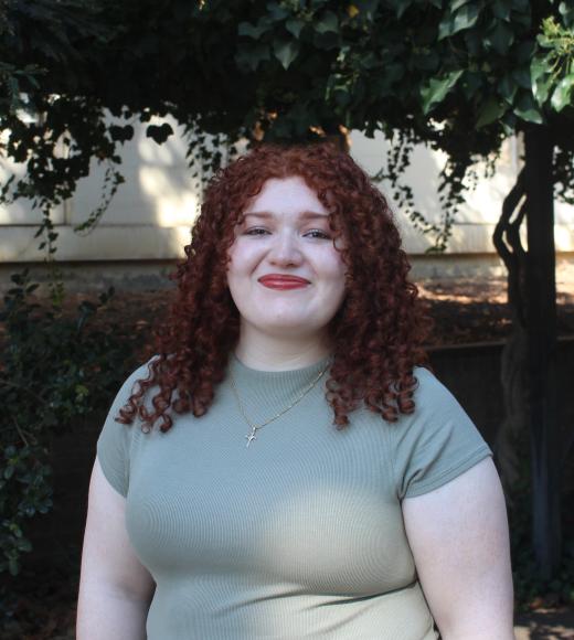 Keren smiling warmly in front of greenery background,
