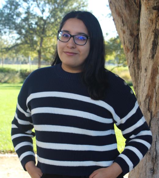 Joyce standing in front of a tree. Greenery background.