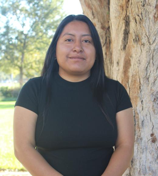 Guadalupe standing in front of a tree. Greenery background.