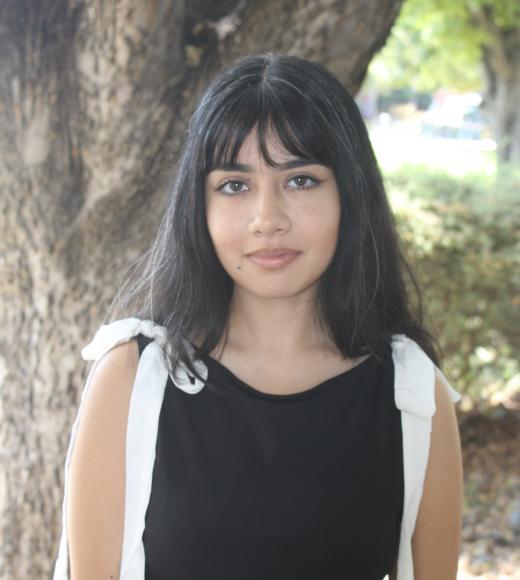 Samantha standing in front of a tree. Greenery background.