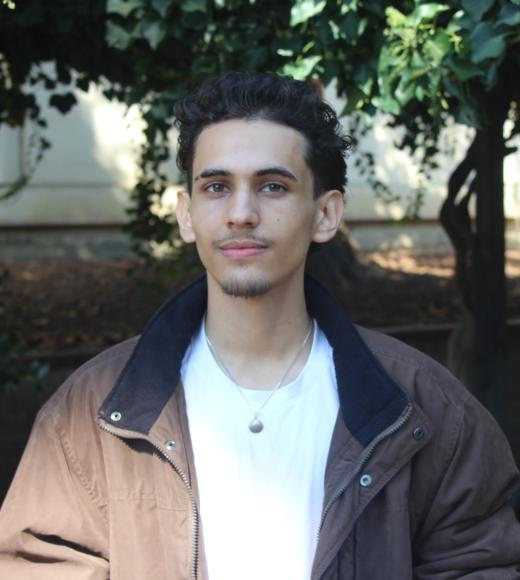 Atl smiling warmly with a greenery background.