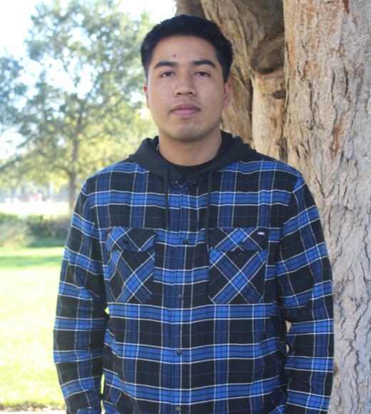 Gustavo standing in front of a tree. Greenery Background.