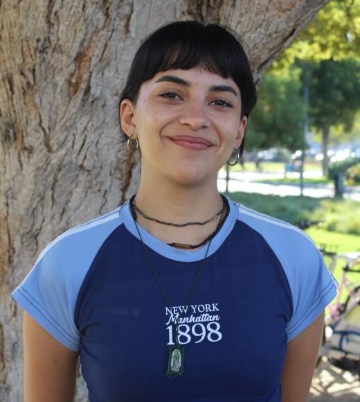 Susy standing in front of a tree. Greenery background.