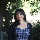 Sarai smiling warmly in front of greenery background