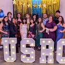 A team photo of USRC team members in at the Center's 10th celebration. Members are standing behind light up letters "USRC".