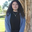 Danna standing in front of a tree. Greenery background.