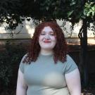 Keren smiling warmly in front of greenery background,