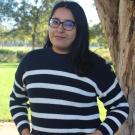 Joyce standing in front of a tree. Greenery background.