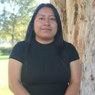 Guadalupe standing in front of a tree. Greenery background.