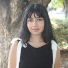 Samantha standing in front of a tree. Greenery background.