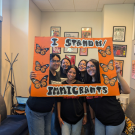 SPEAK student members posing in front of a frame that read "I Stand With Immigrants" from UndocuWelcome 2024