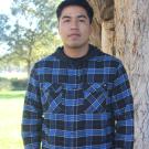 Gustavo standing in front of a tree. Greenery Background.